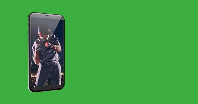 A mobile phone with celebrating baseball player on the screen. A phone is over green background.