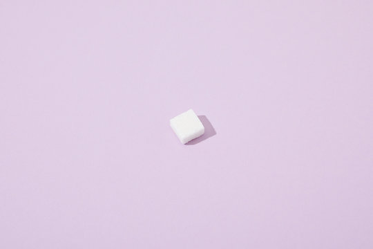 lump sugar cube on violet background with copy space