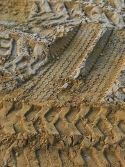 The tire marks are imprinted on the sand floor at the construction site.