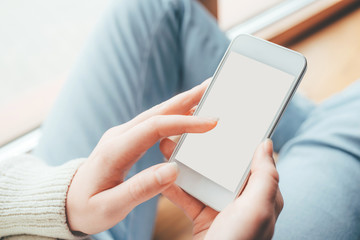 Woman's hands holding phone with white screen. Copy space for your text message.