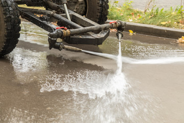 Washing roads in the city with harvesting equipment. Disinfection of roads and sidewalks. Сoncept of visiting public places as a pre-official measure against the COVID-19 coronavirus