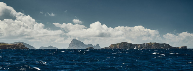 The Landscape of the balearic sea and improbable mountains, azure water, the storm sky, lonely boat on the horizon