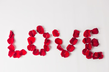 background texture LOVE inscription made of red rose petals on a white background