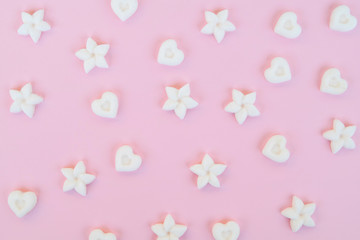Top view on sugar in the shape of heart and flower on a pink background