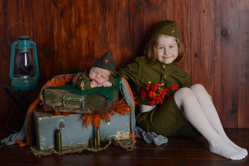 a newborn child and his sister are sitting at home, children in uniform, Victory Day May 9, 1941-1945 in Russia, military children