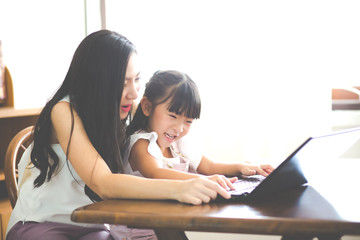 Happy mother and daughter using the laptop at home. Work from home and social distancing concept