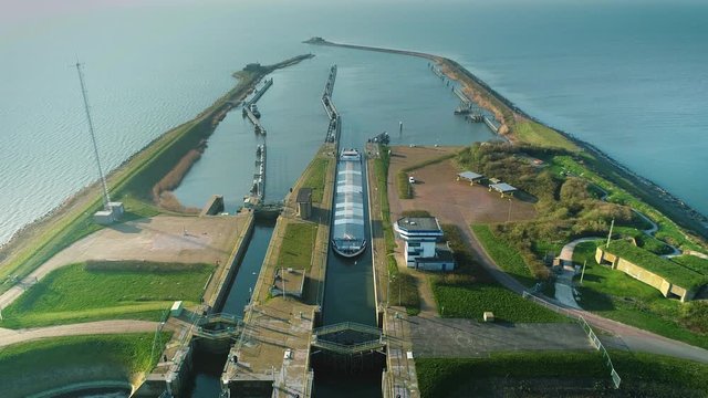 [One Minute Video] Enclosure Dam (Afsluitdijk): Large Cargo Ship Carefully Entering Sluice to Cross the Enclosure Dam, Overview - Friesland, Netherlands / Holland &ndash; 4K Drone Footage