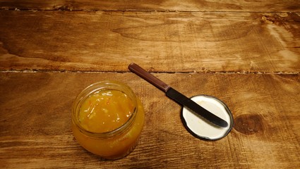 Jar of orange jam on dark wood