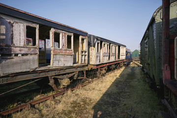 Fototapeta na wymiar Abandoned train depot with various trains and carriages in different states of decay.