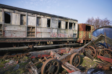 Abandoned train depot with various trains and carriages in different states of decay.