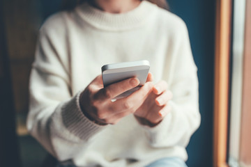 Women's hands use a smartphone for online shopping, social networking, or remote work. Close up image.