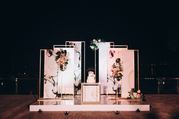 wedding cake stands in an area decorated with designer panels and flower arrangements