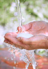 a person washes his hands under a stream of clean water with soap