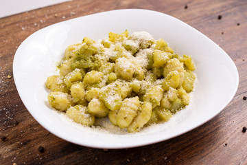 Italian homemade gnocchi with basil sauce and potatoes. Traditional dish of Italian cuisine, vegetarian food.
