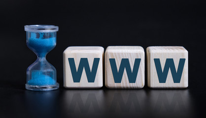 WWW - World wide web - concept with an hourglass. Wooden cubes on a black table