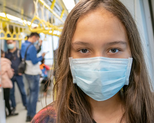 Fototapeta na wymiar Young tween girl wearing surgical mask on subway