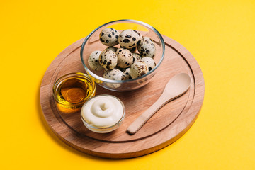 Quail eggs in a plate with mayonnaise and butter on a yellow background with place for text