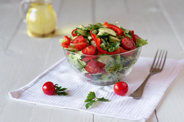 Salad on a white wooden background from tomatoes, cucumber, lettuce and red pepper. Healthy eating concept.