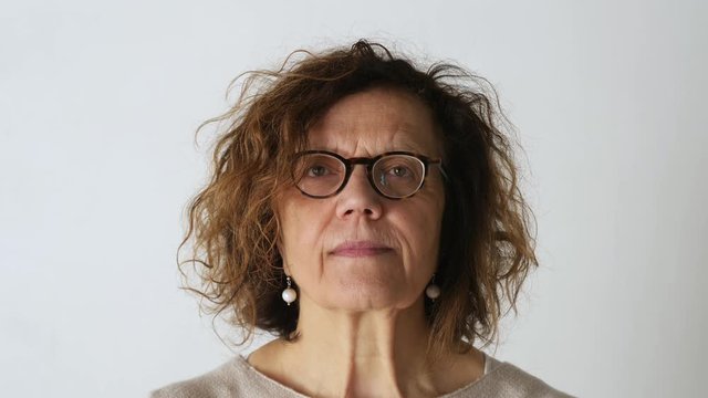 Middle aged woman looking on camera isolated on a grey background, shot in 4K