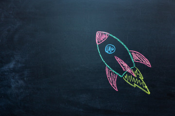 Chalk space rocket painted on school chalkboard.