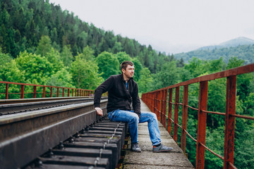 Handsome man on railway track on forest background