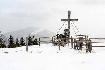 summit cross on "Hochanger" mountain and the "Hochschwab" mountainrange in the background in styria, Austria in winter