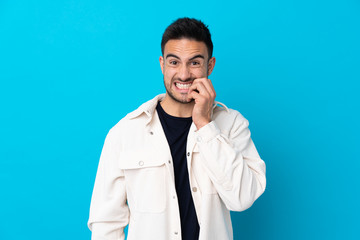 Young handsome man over isolated blue background nervous and scared