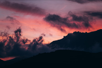 saturated orange-purple mountain landscape with clouds during twilight
