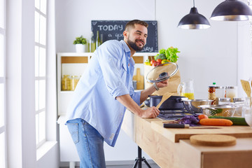 Smiling and confident chef standing in a large kitchen tasting a cooked dish