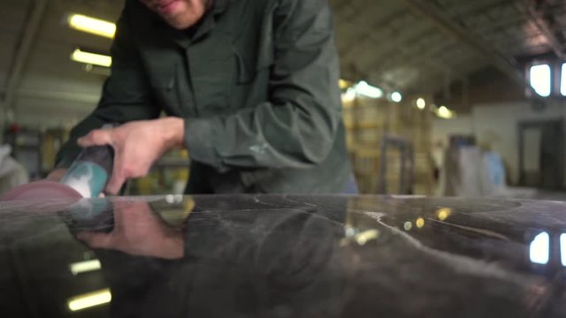  Worker in a green jacket polishes a marble table in a factory. Super Slow Motion