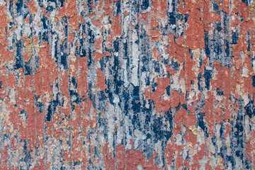 Fragment of shabby wall with striped base with old peeling paint for the background. Backdrop abstraction with exfoliation, swelling and cracks. Primary colors - wilted brown, redwood, Oxford blue.