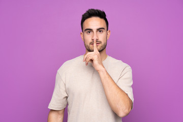 Young handsome man over isolated purple background showing a sign of silence gesture putting finger in mouth