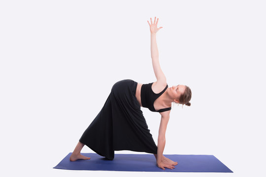 Photo of young sport woman doing yoga on mat over white background in studio