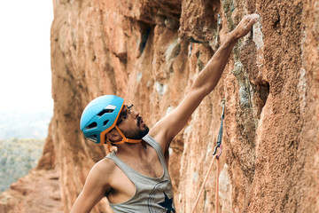 Escalador agarrando roca con una mano y mirando ruta