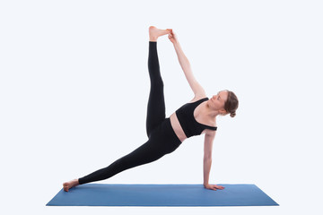 Photo of young sport woman doing yoga on mat over white background in studio