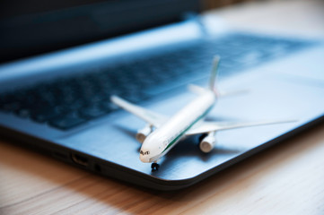 Airplane model with laptop computer on wooden table. Composition with toy plane and laptop on...