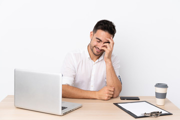 Young business man with a mobile phone in a workplace laughing