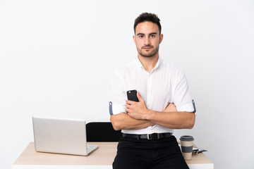 Young business man with a mobile phone in a workplace keeping arms crossed