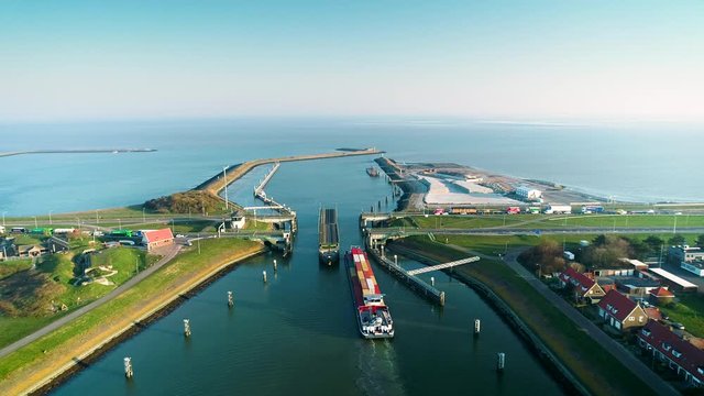 Enclosure Dam (Afsluitdijk): Large Cargo Ship Passing Through the Enclosure Dam, Bridge is Open by Turning the Road 180 Degrees, Zooming In - Friesland, Netherlands / Holland &ndash; 4K Drone Footage