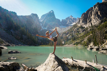 Woman doing yoga by the glacier lake in the mountains
