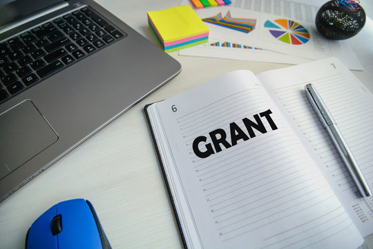 Workspace (desk) with notebook, mouse, diary with word Grant