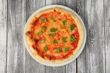 Pizza with tomato sauce and basil on wooden background. Top view, close-up