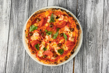 Pizza with tomatoes, cheese and basil on wooden background. Closeup, top view