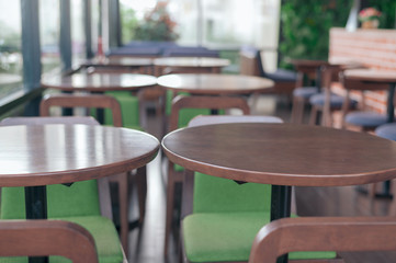 Closeup of round wooden tables in cafe with blurred window and chairs background, Vintage style  