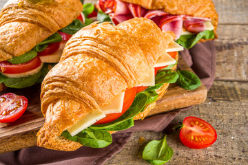 Homemade croissant sandwiches with ham, cheese, fresh vegetables and herbs,