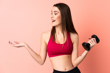 Young sport woman making weightlifting over isolated pink background with surprise facial expression