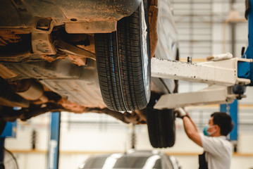 Asian car mechanic is changing a new tire at a tire changing service shop using an air gun to shoot the wheel knot.