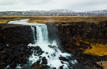 A photographer trying to capture a spectalcular waterfall in Thingvellir, Iceland