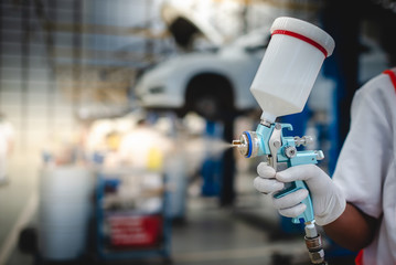 Asian workers stand to hold a spray gun, antiseptic spray gun or car paint gun in protective...