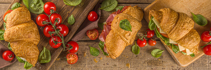 Homemade croissant sandwiches with ham, cheese, fresh vegetables and herbs,